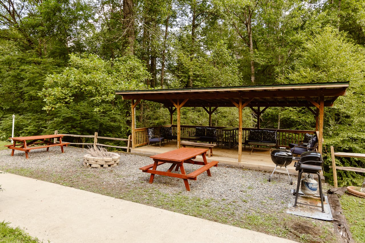 The covered pavilion with picnic tables, grills and a stone fire ring in front