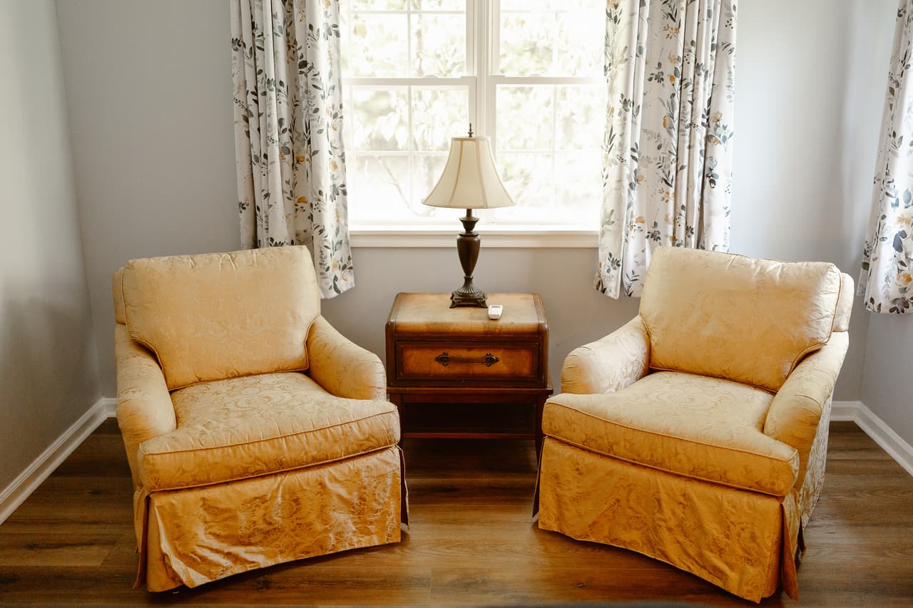 Two upholstered armchairs either side of a small table under the window in the Hideaway Suite